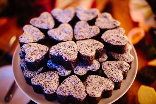A stack of heart-shaped chocolate brownies with white dusting sugar displayed on a white platter