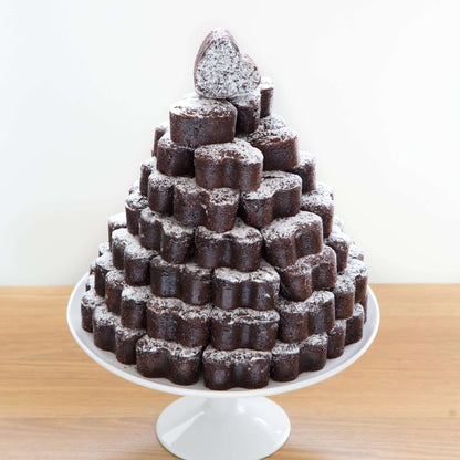 A cake tower made of individual heart-shaped chocolate brownies on a white cake platter
