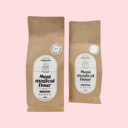Two bags of Most Magical gluten free flour packaged in brown bags with white labels, on a pink background